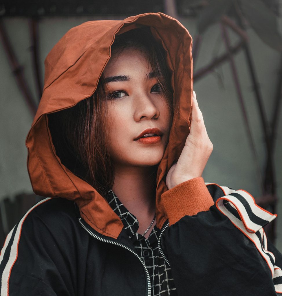 Close-up of a young woman in a fashionable hooded jacket. Outdoor setting.